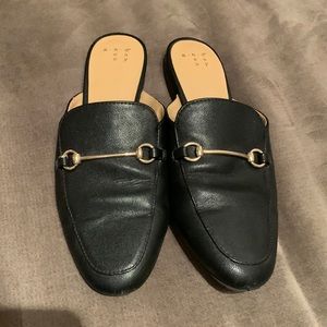 Black mules with gold detail.